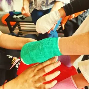 Här anlägger en elev på Real-gymnasiet det yttersta lagret, elastisk binda, på sitt tassbandage. En annan elev ställer upp med sin hand för övningen.